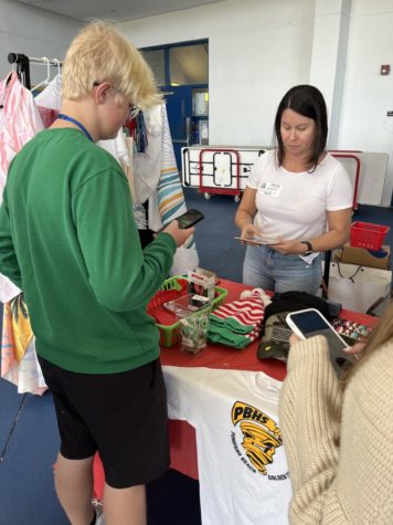 Santa app. Freshman Bjorn Berger uses his Apple Pay to make a purchase from PTSA member Denia Perloff in the courtyard during lunch on Dec. 17. The PTSA ran a holiday shop the week before midterms to raise money for the school. 
