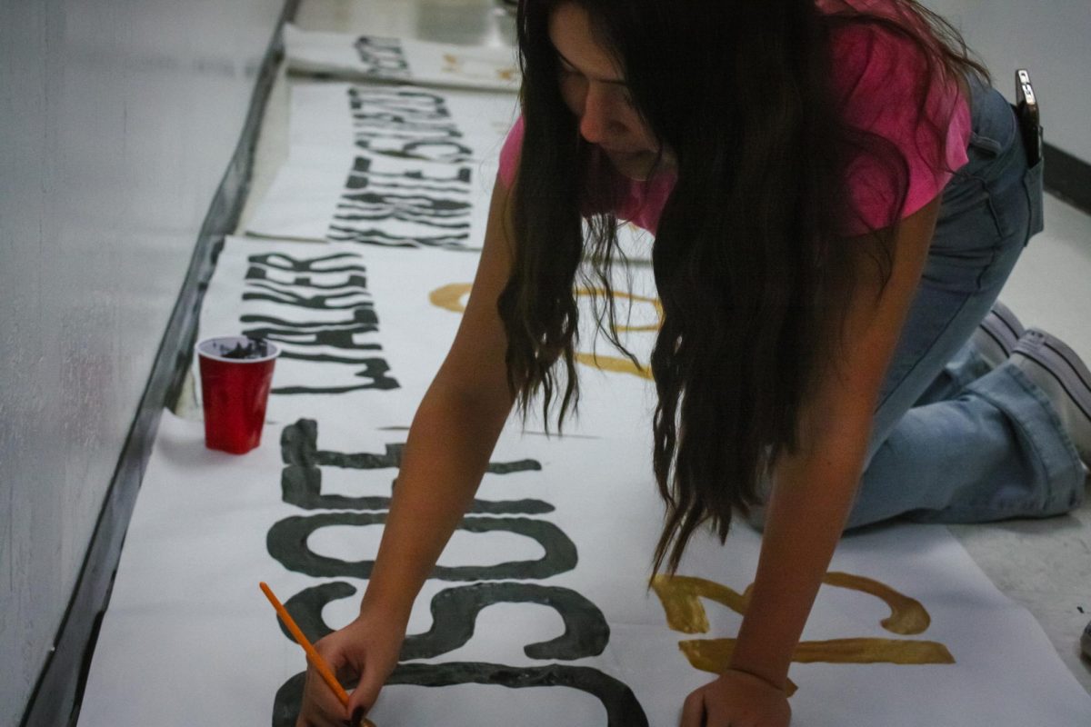 Junior Meera Ghanem supports the football team by painting banners for upcoming football game.